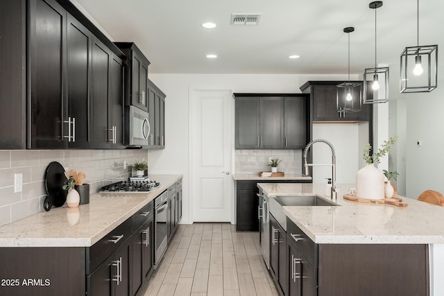 17652 W Fetlock Trl, Surprise, AZ 85387 - kitchen featuring appliances with stainless steel finishes, tasteful backsplash, recessed lighting, a kitchen island with sink, and light stone countertops