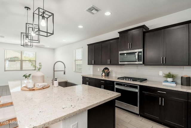 17652 W Fetlock Trl, Surprise, AZ 85387 - kitchen featuring stainless steel appliances, tasteful backsplash, light stone counters, plenty of natural light, and recessed lighting