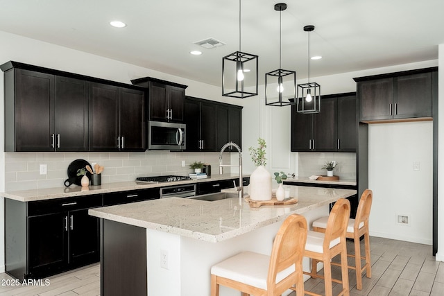 17652 W Fetlock Trl, Surprise, AZ 85387 - kitchen with appliances with stainless steel finishes, dark cabinets, light wood-style floors, backsplash, and recessed lighting