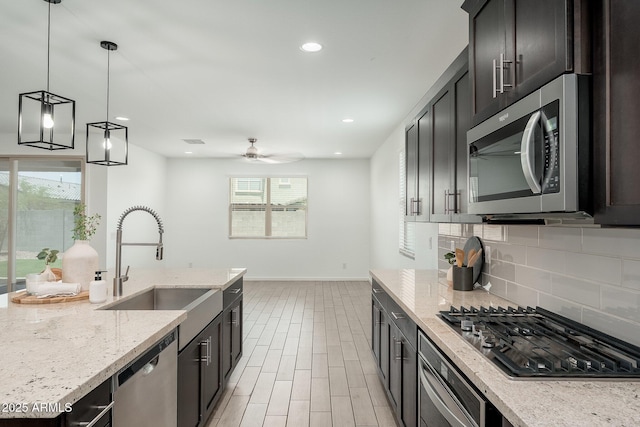 17652 W Fetlock Trl, Surprise, AZ 85387 - kitchen featuring appliances with stainless steel finishes, backsplash, ceiling fan, light stone counters, and decorative light fixtures