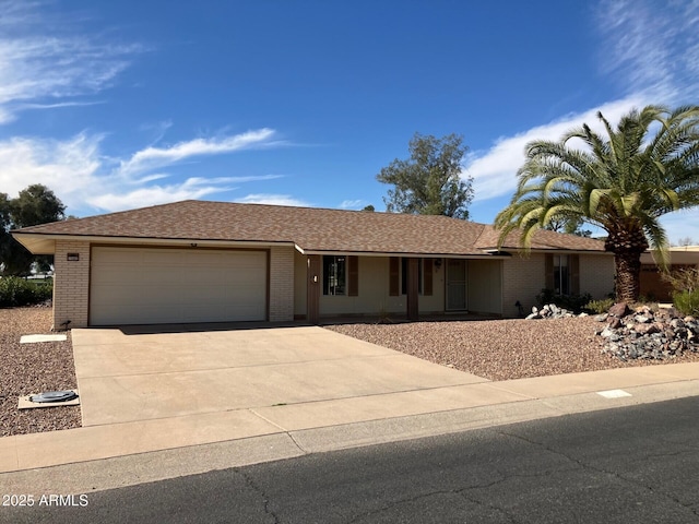 single story home featuring a garage, concrete driveway, brick siding, and roof with shingles