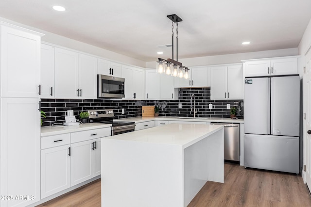 kitchen featuring a center island, sink, pendant lighting, white cabinets, and appliances with stainless steel finishes