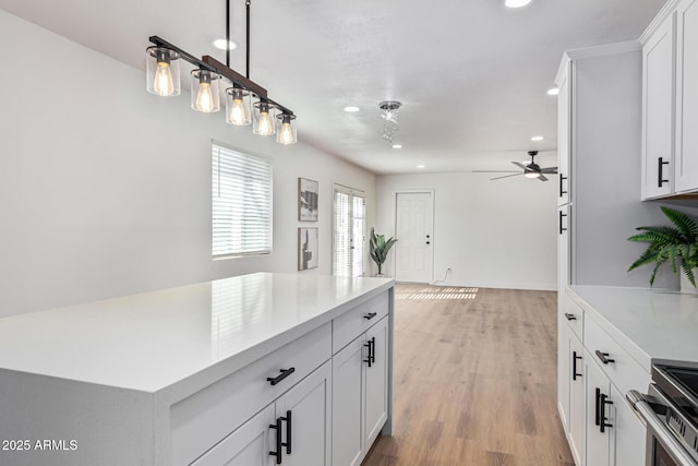 kitchen featuring ceiling fan, white cabinets, and light wood-type flooring