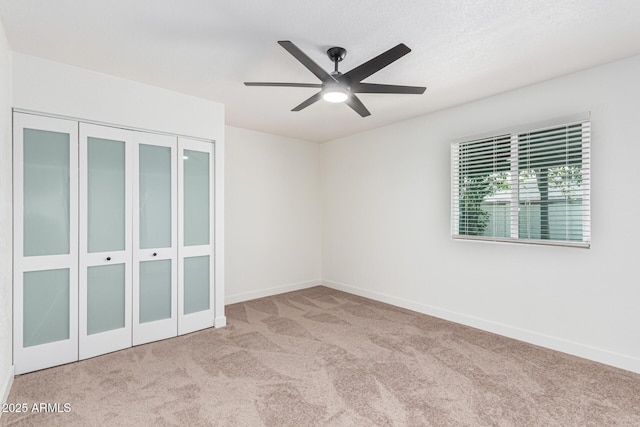 unfurnished bedroom featuring ceiling fan, a closet, and light colored carpet