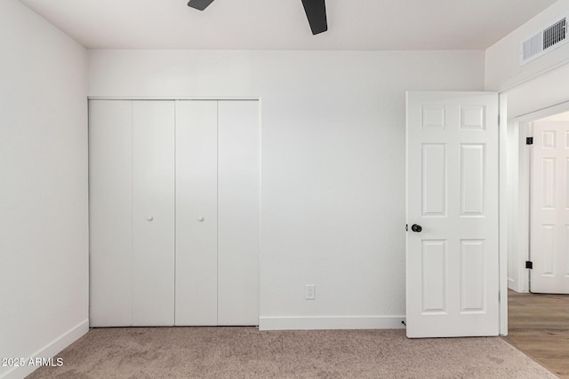 unfurnished bedroom featuring a closet, ceiling fan, and light colored carpet