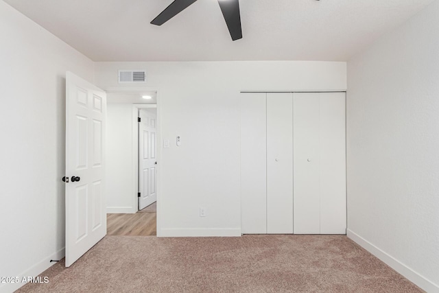 unfurnished bedroom with ceiling fan, a closet, and light carpet