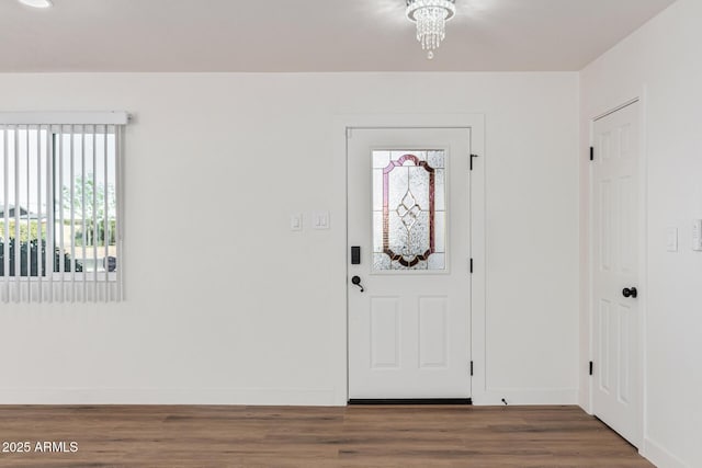 foyer with dark wood-type flooring and an inviting chandelier