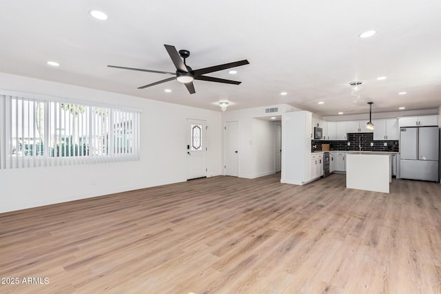 unfurnished living room featuring ceiling fan and light hardwood / wood-style flooring