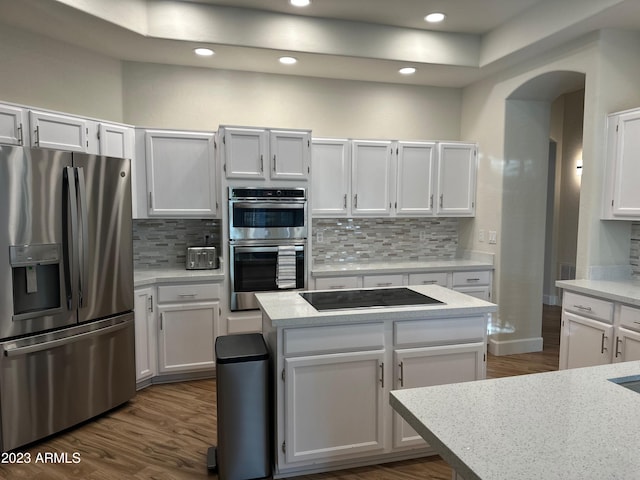 kitchen with tasteful backsplash, a center island, stainless steel appliances, white cabinets, and dark wood-type flooring