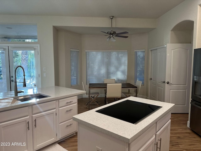 kitchen featuring white cabinets, a center island with sink, wood-type flooring, black electric stovetop, and sink