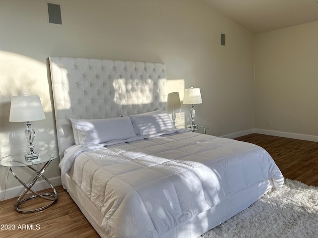 bedroom with vaulted ceiling and dark hardwood / wood-style flooring