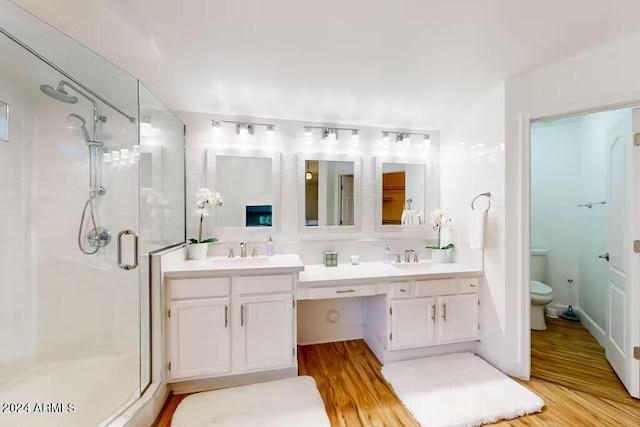 bathroom with a shower with door, vanity, wood-type flooring, and toilet