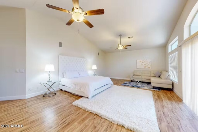 bedroom featuring light hardwood / wood-style floors, multiple windows, high vaulted ceiling, and ceiling fan