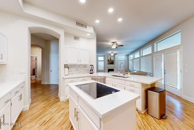 kitchen featuring sink, a center island, kitchen peninsula, black electric cooktop, and white cabinets