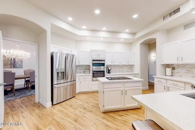 kitchen with decorative backsplash, appliances with stainless steel finishes, light hardwood / wood-style flooring, and white cabinetry