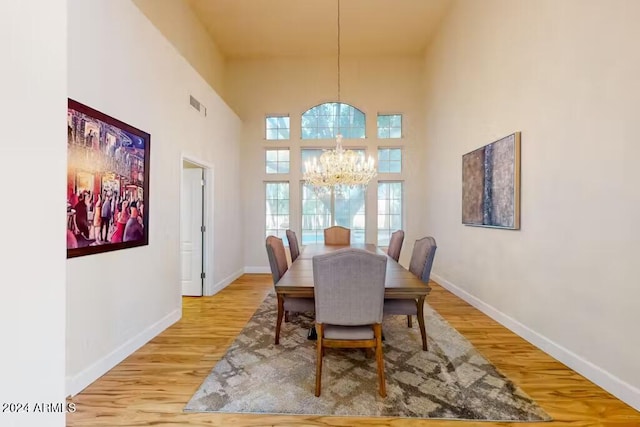 dining area with a notable chandelier, hardwood / wood-style flooring, and a high ceiling