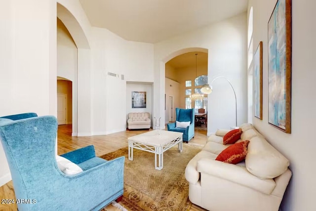 living room featuring a notable chandelier, hardwood / wood-style flooring, and a high ceiling