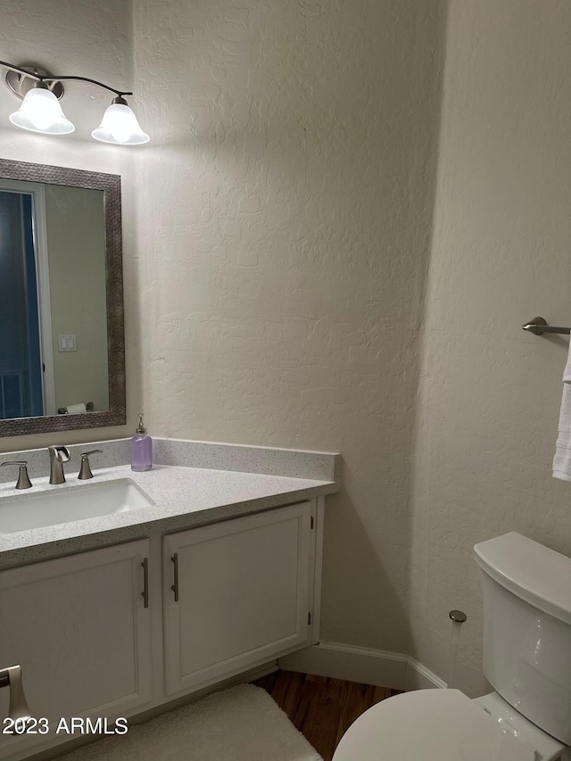 bathroom with toilet, hardwood / wood-style flooring, and vanity