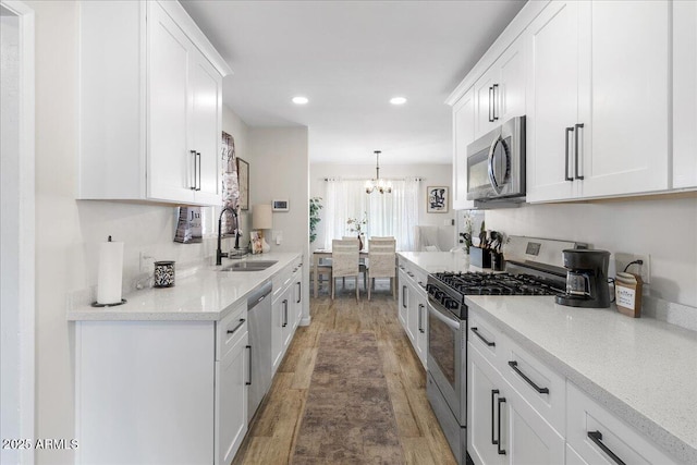 kitchen with stainless steel appliances, sink, hanging light fixtures, and white cabinets