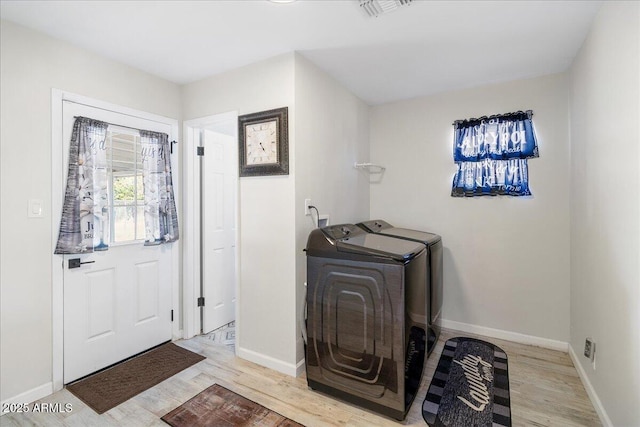 laundry area with washing machine and dryer and light hardwood / wood-style flooring