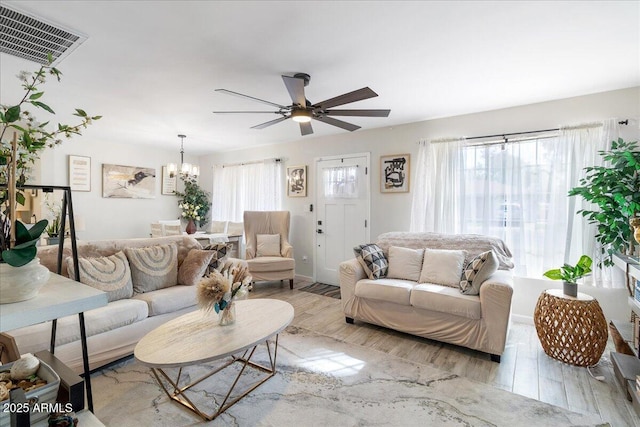 living room with ceiling fan with notable chandelier and light wood-type flooring