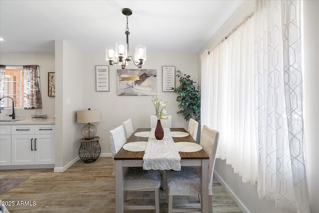 dining room featuring sink, a notable chandelier, and light hardwood / wood-style floors