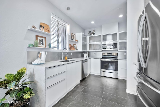 kitchen featuring sink, appliances with stainless steel finishes, dark tile patterned flooring, pendant lighting, and white cabinets