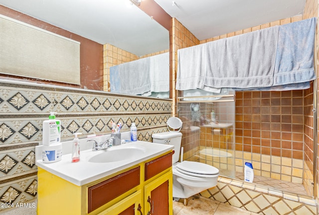 bathroom featuring vanity, toilet, a tile shower, tile walls, and tile patterned flooring