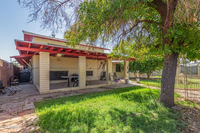 rear view of property featuring cooling unit, a lawn, a patio area, and ceiling fan