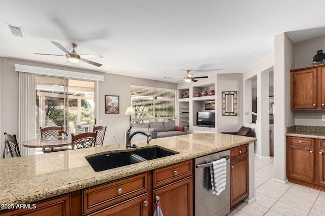 kitchen featuring sink, light stone counters, light tile patterned floors, stainless steel dishwasher, and built in features