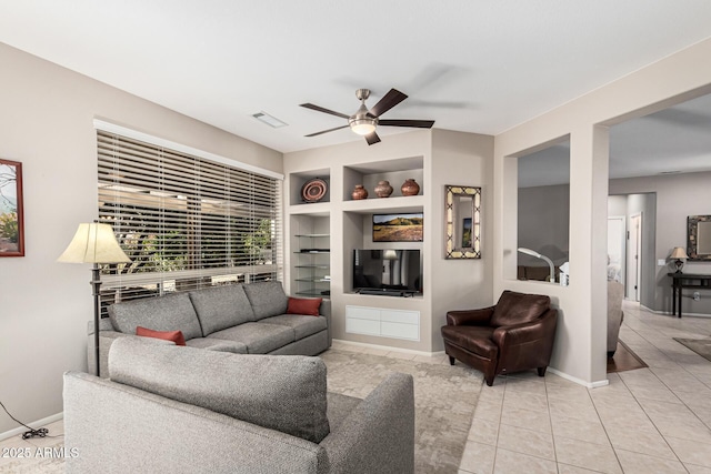 tiled living room featuring built in shelves and ceiling fan