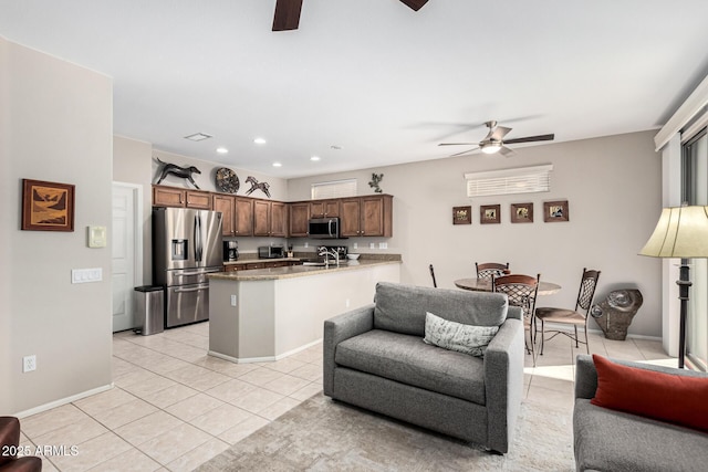 kitchen featuring sink, ceiling fan, appliances with stainless steel finishes, light tile patterned flooring, and kitchen peninsula