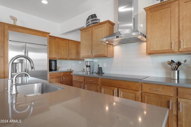 kitchen featuring built in fridge, extractor fan, tasteful backsplash, sink, and black electric cooktop