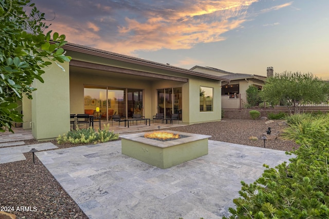 back house at dusk with a fire pit and a patio