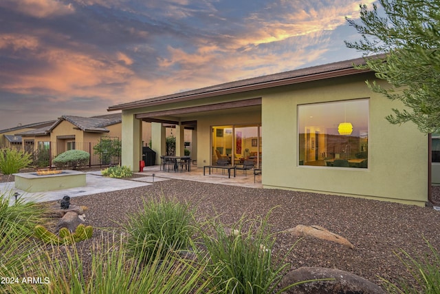 back house at dusk featuring a patio area