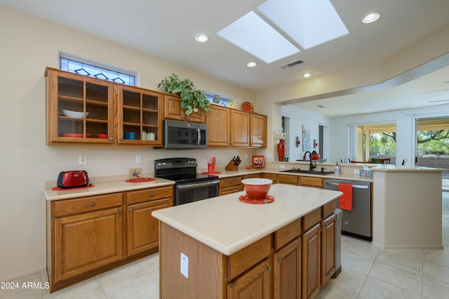 kitchen featuring a center island, sink, a skylight, light tile patterned flooring, and stainless steel appliances