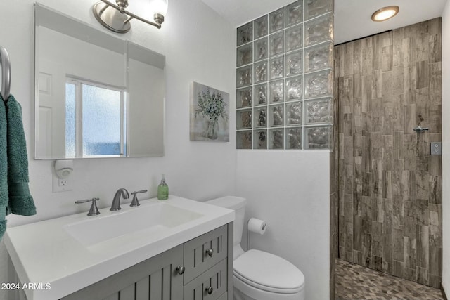 bathroom featuring toilet, vanity, and a tile shower