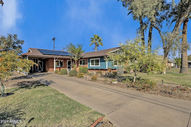 view of front of home featuring a front lawn and solar panels