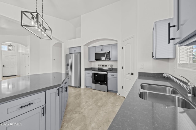 3843 E Citrine Rd, San Tan Valley, AZ 85143 - kitchen with stainless steel appliances, a sink, arched walkways, pendant lighting, and dark stone counters