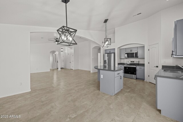 3843 E Citrine Rd, San Tan Valley, AZ 85143 - kitchen with appliances with stainless steel finishes, arched walkways, a sink, dark countertops, and a kitchen island