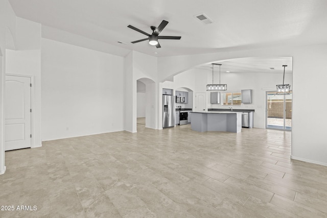 3843 E Citrine Rd, San Tan Valley, AZ 85143 - unfurnished living room featuring a ceiling fan, vaulted ceiling, arched walkways, and a chandelier