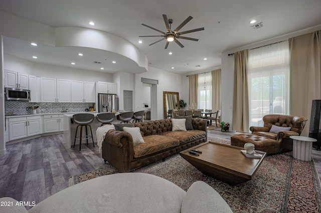 living room with a towering ceiling, ceiling fan, and dark hardwood / wood-style flooring