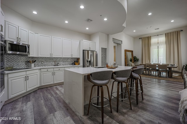 kitchen featuring backsplash, white cabinets, a kitchen island with sink, and stainless steel appliances