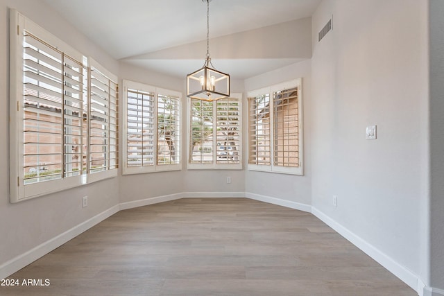 interior space with hardwood / wood-style flooring, vaulted ceiling, and a notable chandelier