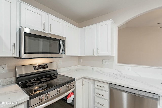 kitchen with light stone counters, white cabinets, and appliances with stainless steel finishes