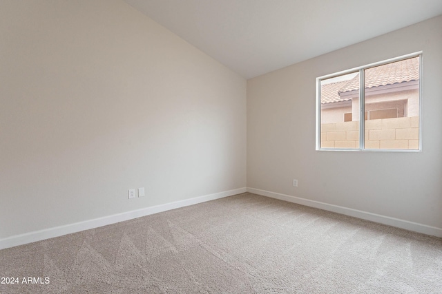 carpeted empty room with vaulted ceiling