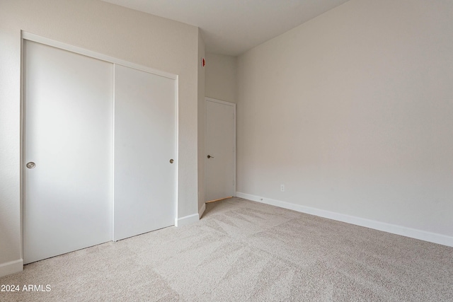 unfurnished bedroom with light carpet and a closet