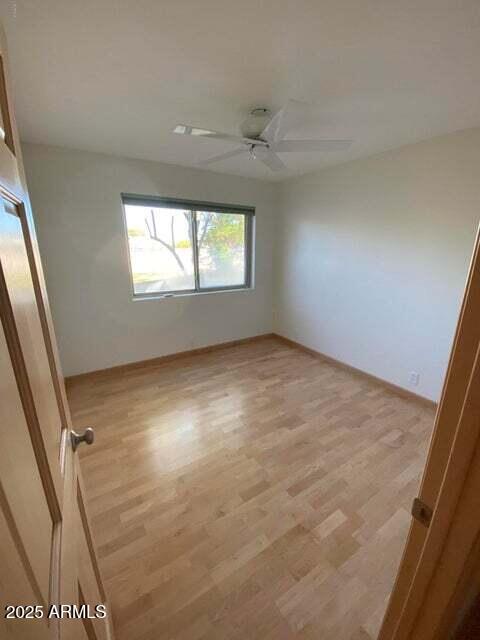 unfurnished room featuring light wood finished floors, ceiling fan, and baseboards