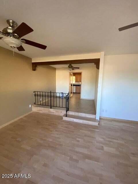 empty room featuring a ceiling fan, baseboards, and wood finished floors