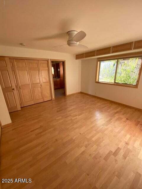 unfurnished bedroom with light wood-style flooring, baseboards, and a ceiling fan